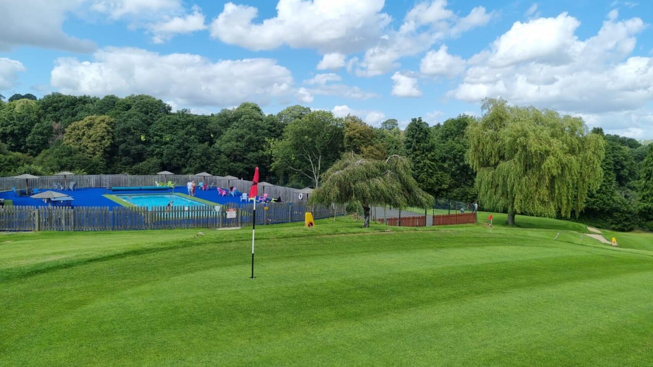 The first green on Bank farm's pitch and putt golf course with the swimming pool beyond.