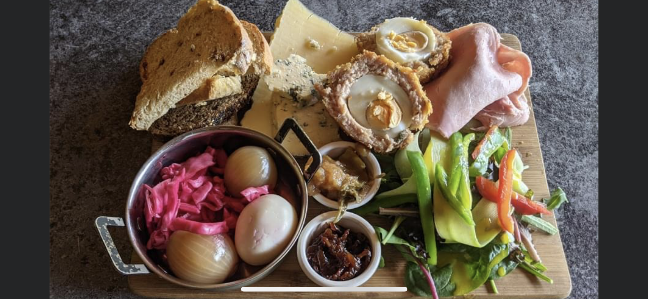 Food board with scotch eggs, pickles and salad