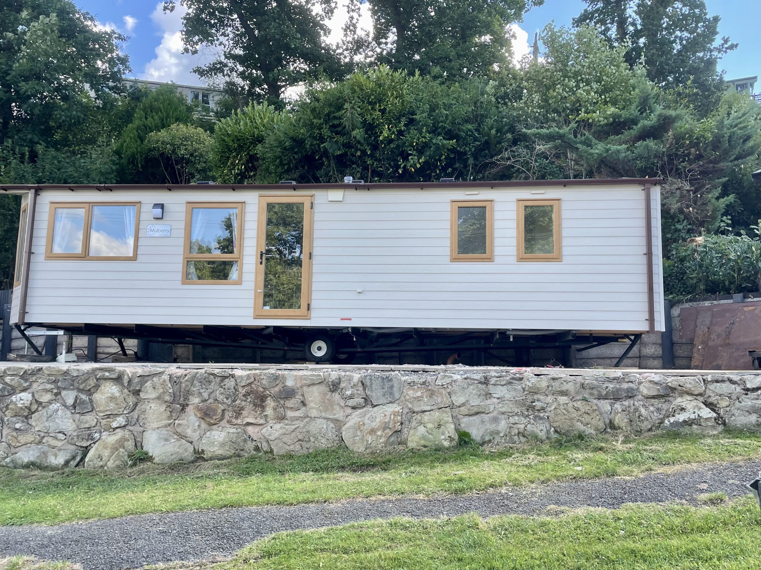 Side on static caravan fset on a grey wall with path infront and green grassor sale