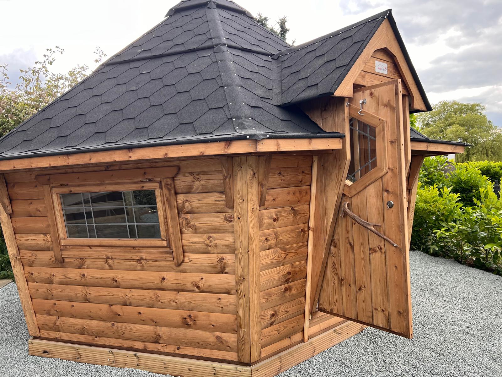 The pointed roof party hut with a grey roof and wooden boards