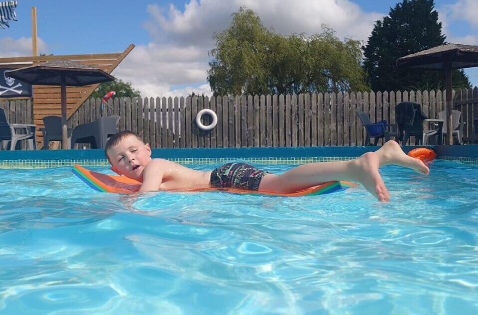Bank fam swimming pool with boy snoozing on lilo