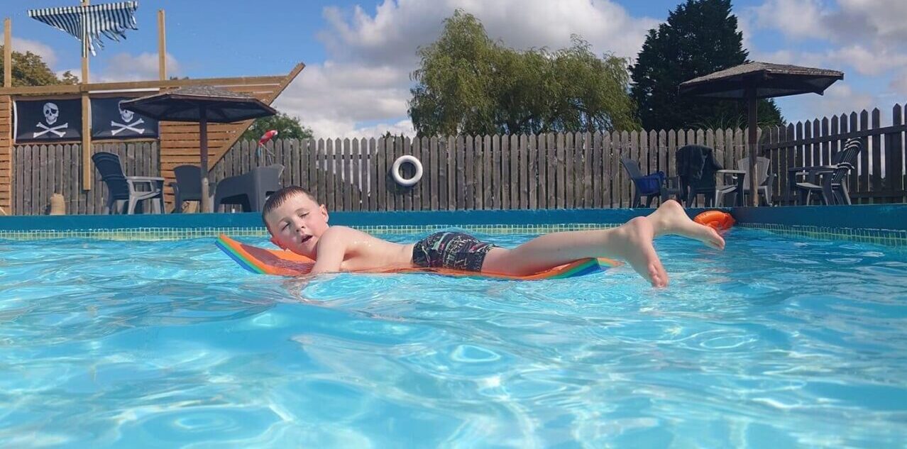 Bank fam swimming pool with boy snoozing on lilo